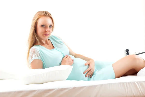 Ernste langhaarige pregnt Mädchen im Nachthemd im Bett — Stockfoto