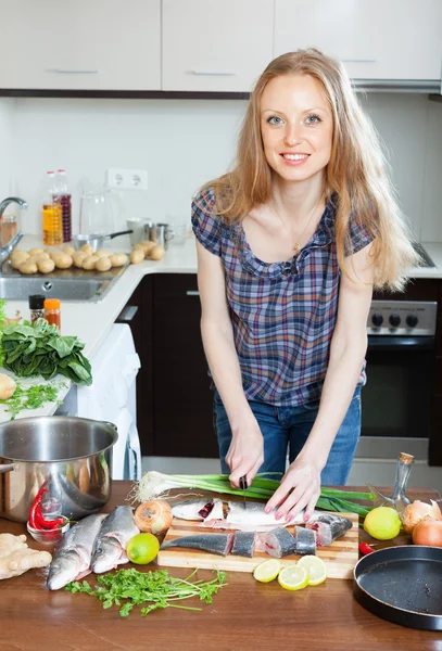 Žena krájení syrové ryby v kuchyni — Stock fotografie