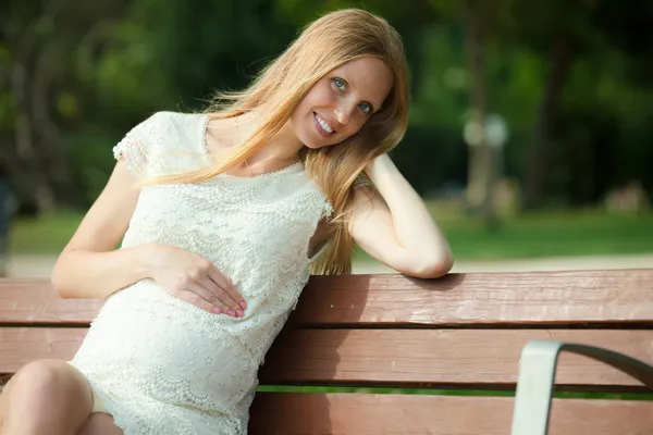孕妇在夏天的公园长凳上 — 图库照片