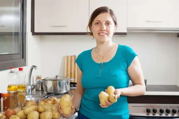 Jonge huisvrouw aardappelen koken — Stockfoto