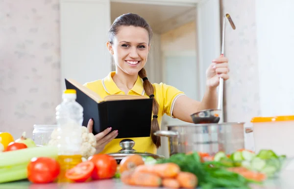Huisvrouw leest kookboek voor recept — Stockfoto