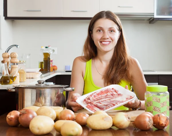 Mulher feliz cozinhar com carne de cordeiro — Fotografia de Stock