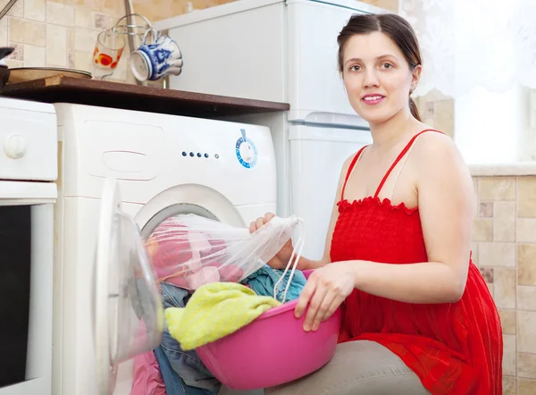 Dona de casa em vermelho carregando a máquina de lavar roupa — Fotografia de Stock