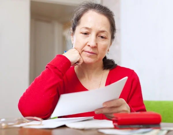 Serious woman reads payment bills — Stock Photo, Image