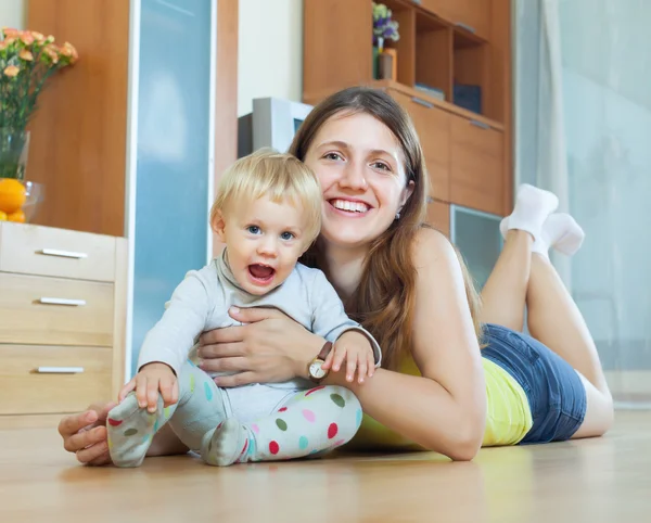 Happy long-haired mom and child on wooden floor — Stock Photo, Image