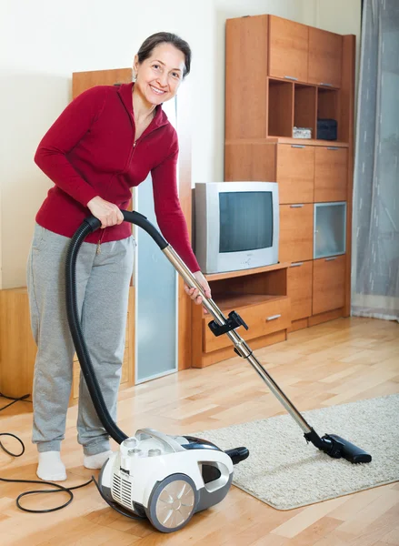 Happy mature woman cleaning with vacuum cleaner — Stock Photo, Image