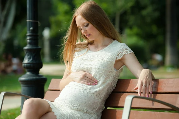 Ciąża kobieta siedzi na ławce — Zdjęcie stockowe