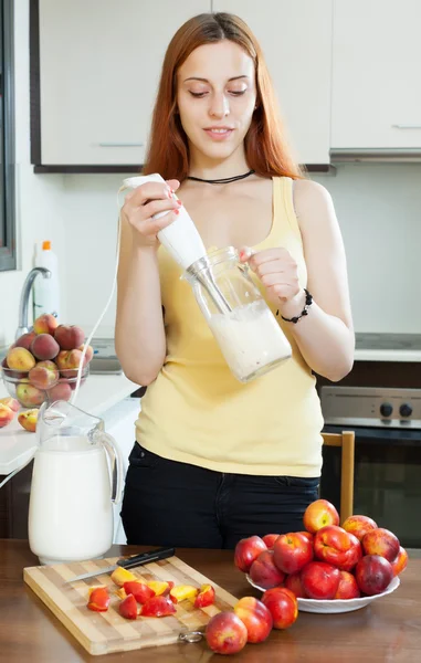 Mulher que cozinha bebidas com liquidificador de nectarinas — Fotografia de Stock