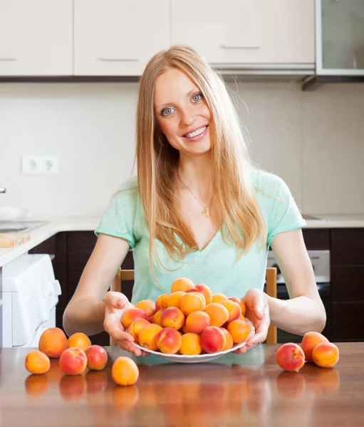 Blonde girl near heap of apricots — Stock Photo, Image