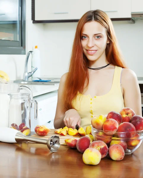 Vrolijke houswife koken met perziken — Stockfoto