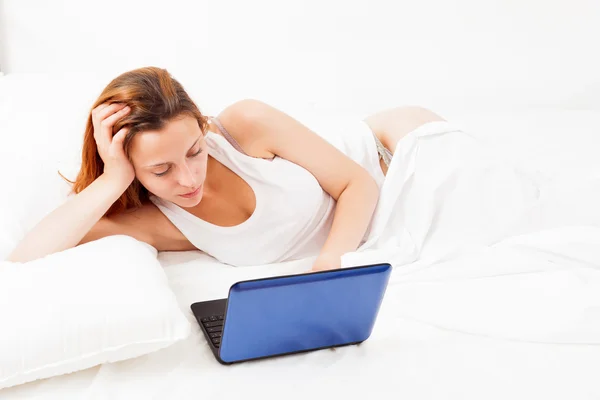 Flicka med laptop ligga i sin säng — Stockfoto