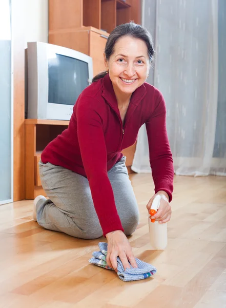 Šťastný zralá žena odření dřevěná podlaha — Stock fotografie