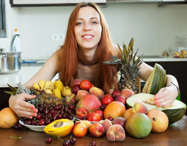 Happy long-haired girl with heap of fruits — Stock Photo, Image