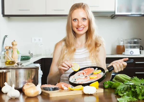 Mujer sonriente cocinando salmón con limón — Foto de Stock