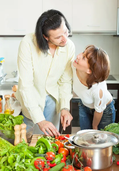 Uma mulher e um homem com legumes na cozinha — Fotografia de Stock