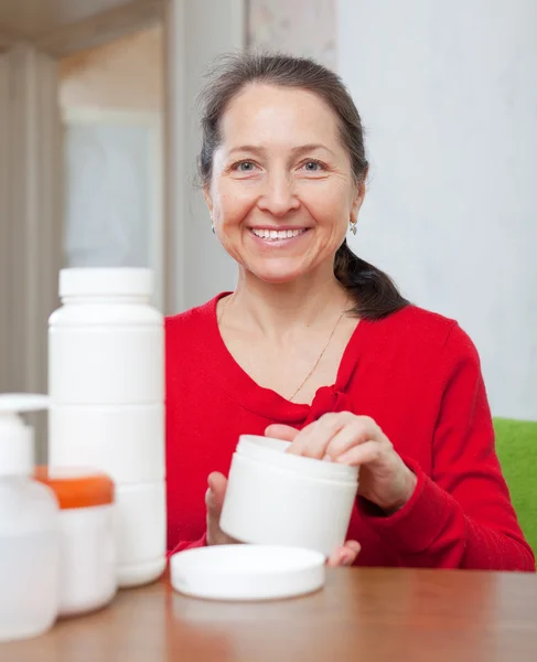 Mujer madura utiliza crema cosmética — Foto de Stock