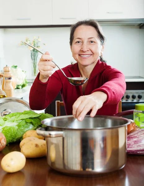 Donna matura aggiungendo condimento in minestra dieta prestata — Foto Stock