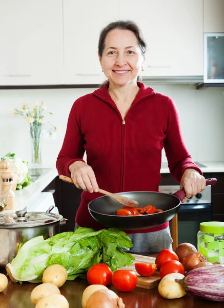 Donna matura positiva che cucina con padella — Foto Stock