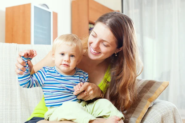 Long-haired mother with toddler on sofa — Stock Photo, Image