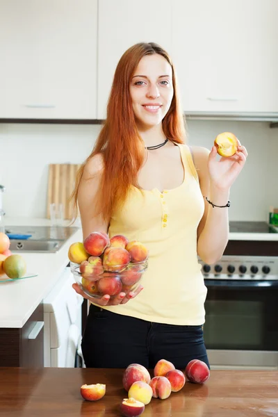 Pretty girl in yellow eats peaches — Stock Photo, Image
