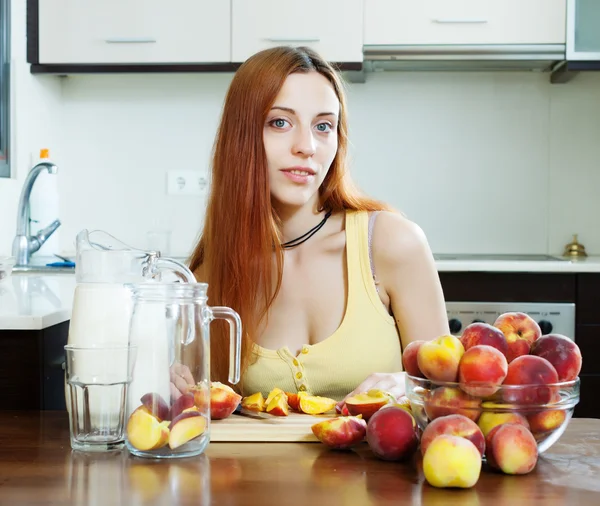 Vrouw dranken met perziken thuis koken — Stockfoto