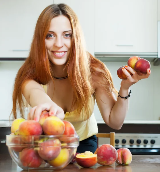 Длинноволосая девушка берет персики — стоковое фото