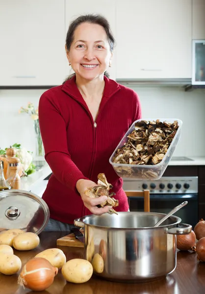 Mature woman cooking soup with dried mushrooms — Stock Photo, Image