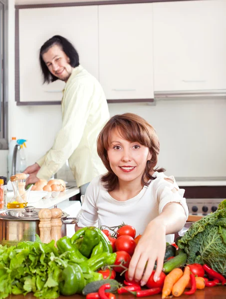 Man och kvinna med grönsaker i kök — Stockfoto