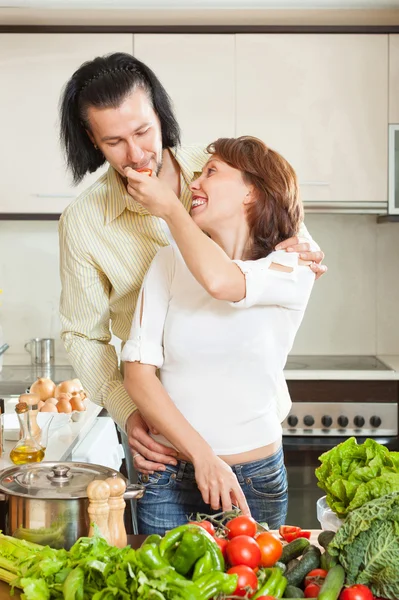 Un hombre y una hermosa mujer con verduras en la cocina —  Fotos de Stock