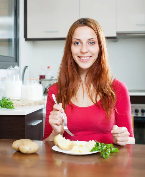 Mulher em vermelho comendo batatas jaqueta em casa — Fotografia de Stock