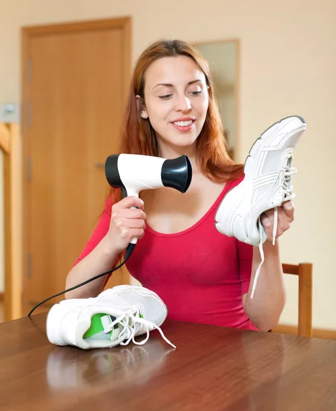 Housewife heating sneakers hairdryer — Stock Photo, Image