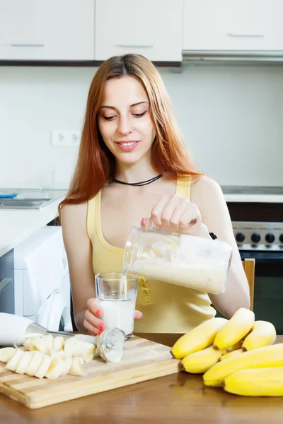 Positive woman making milkshake with bananas — Stock Photo, Image