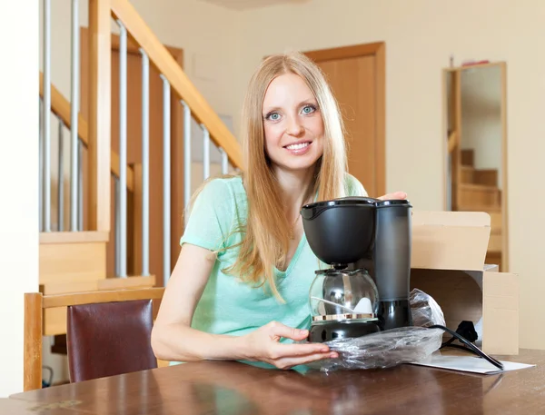 Улыбающийся молодой блондин с новой электрической кофеваркой дома — стоковое фото