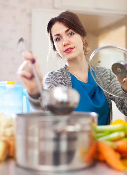 Jovem mulher cozinhar sopa com pá — Fotografia de Stock