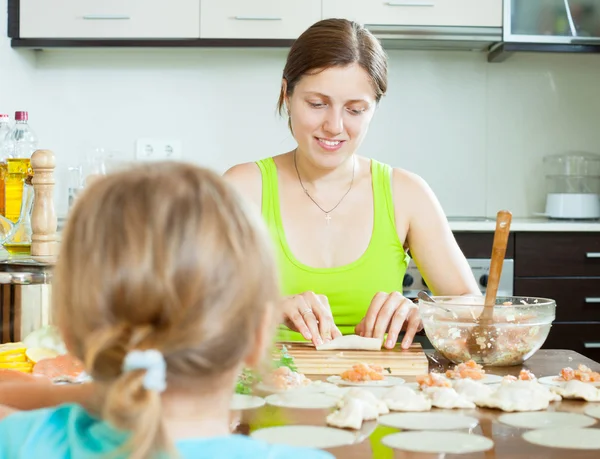 Femme avec un enfant obéissant faire des boulettes de saumon de poisson — Photo