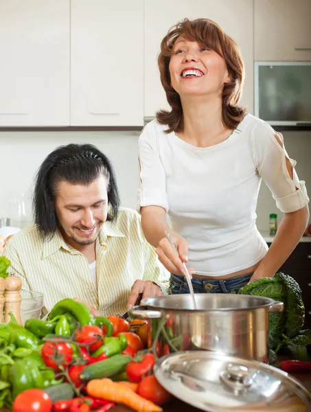 Handsome man and a young woman with vegetables in the kitchen — Stock Photo, Image