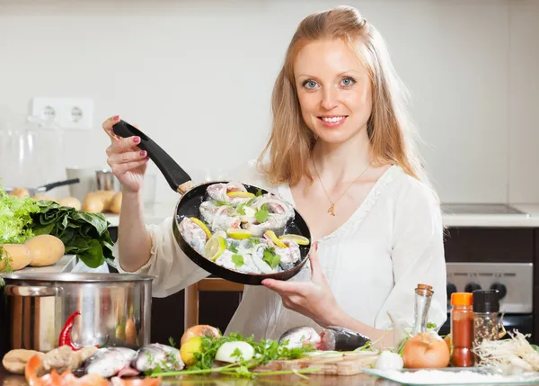 Chica sonriente cocinando pescado con limón — Foto de Stock