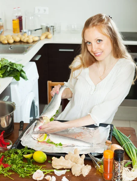 Glückliche Frau kocht Fisch mit Zitrone in Blechpfanne — Stockfoto