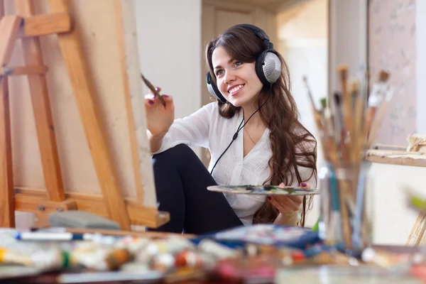 Ragazza in cuffia dipinge con colori ad olio su tela — Foto Stock