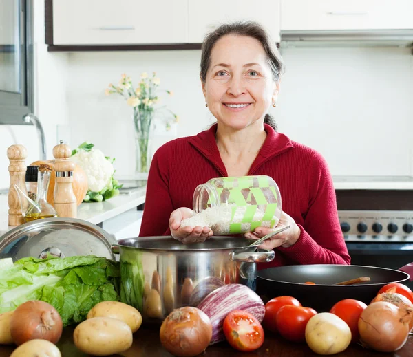 Felice donna matura cucina con riso — Foto Stock