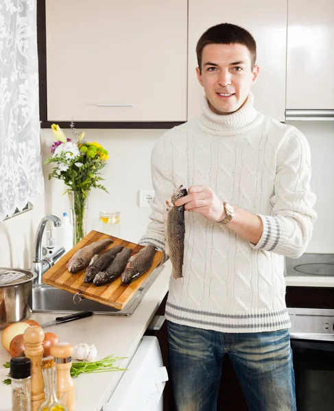 Hombre guapo sosteniendo trucha cruda — Foto de Stock