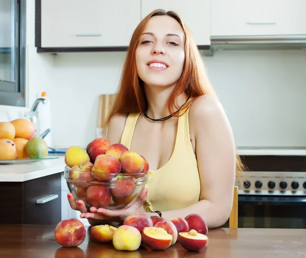 Sorrindo mulher de cabelos longos com pêssegos — Fotografia de Stock