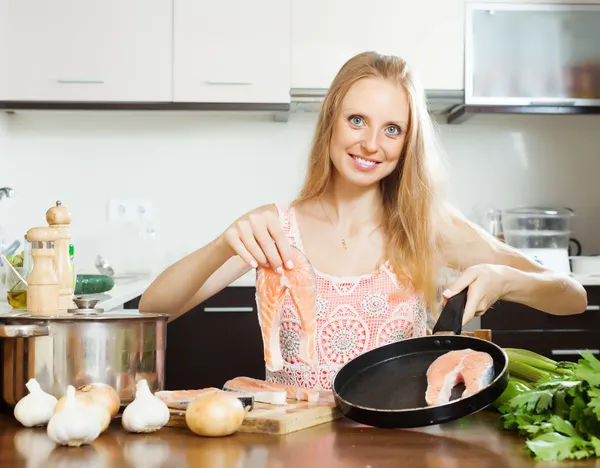 Usmívající se žena v domácnosti, vaření losos — Stock fotografie