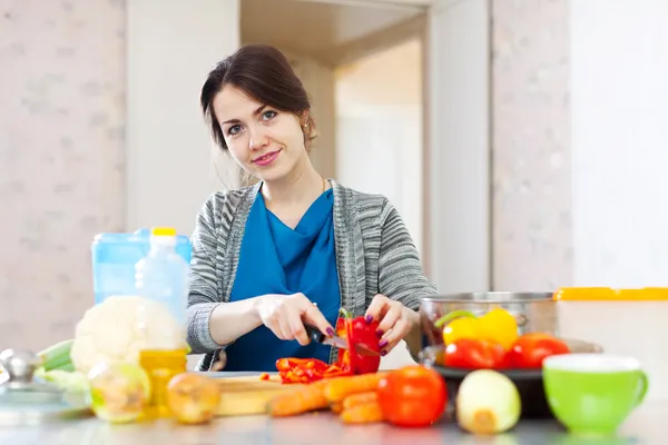 Mulher corta pimenta vermelha na cozinha — Fotografia de Stock