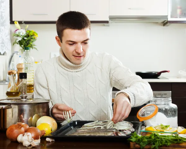 Человек готовит сырую рыбу в сковороде — стоковое фото