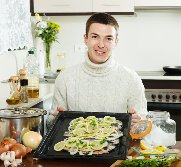 Человек с сырой рыбой на сковороде — стоковое фото
