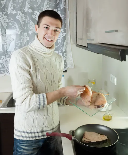 Человек кладет сырой стейк рыбы в сковородку — стоковое фото