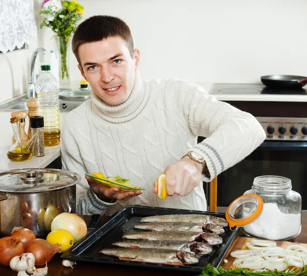 Chico guapo cocinando pescado crudo con limón —  Fotos de Stock