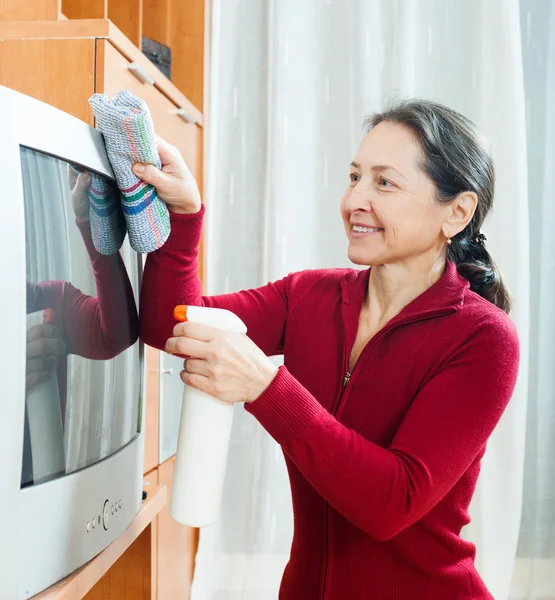 Mature woman cleaning TV — Stock Photo, Image