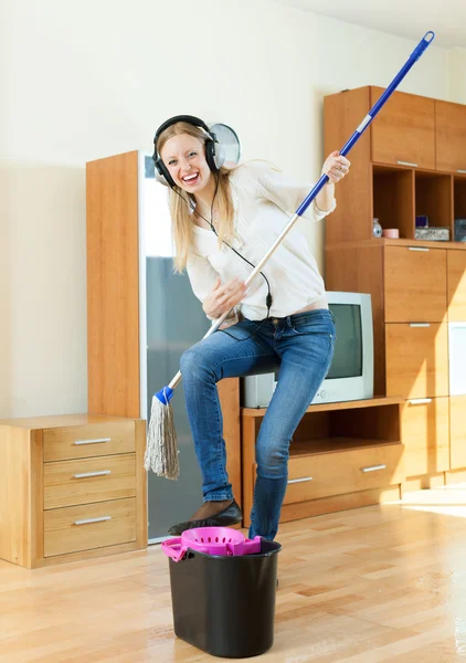 Gelukkige huisvrouw in hoofdtelefoon met mop — Stockfoto